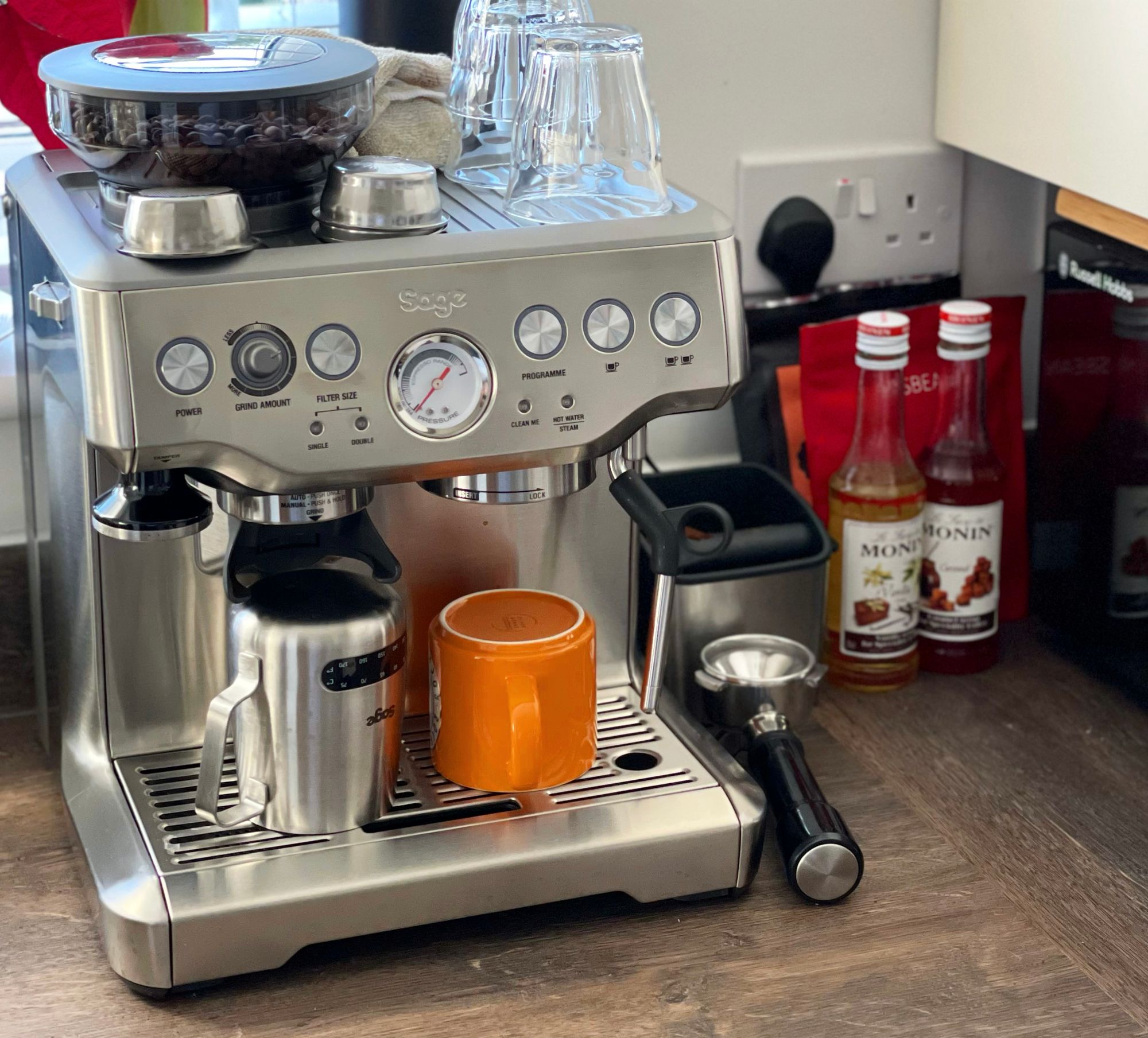 A Sage Barista Express espresso machine on a brown wooden kitchen counter