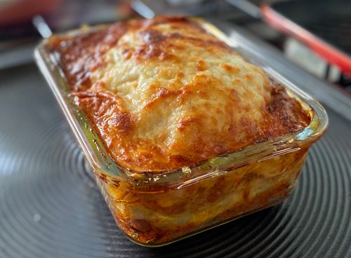 A freshly baked lasagne with a beautiful golden top on a baking tray