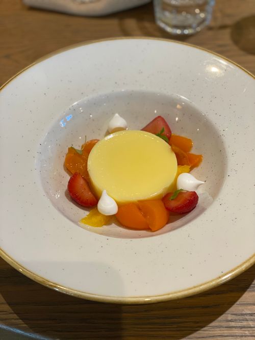 A dessert in an artisan bowl - the dessert is lemon posset with fruits and meringue artfully placed on it